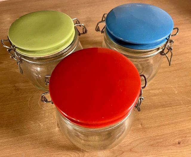 Preview of the first image of GLASS STORAGE JARS WITH COLOURED TOPS.