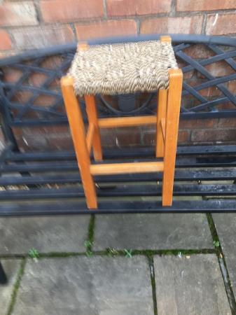 Image 2 of A four legged wooden stool with variegated seat..