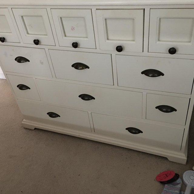 Preview of the first image of A CREAM COLOURED CHEST OF DRAWERS.
