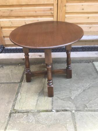 Image 2 of A small , round, wooden coffee table with turned legs.