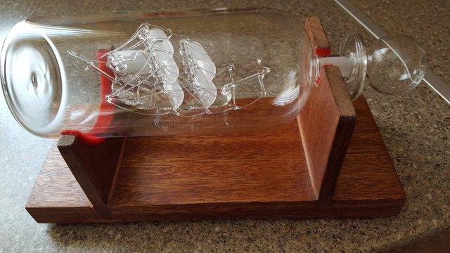 Image 1 of Glass ship in a bottle on solid wood stand