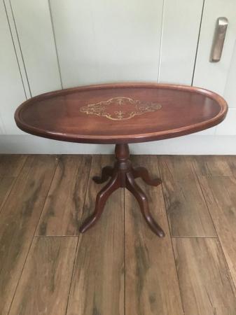 Image 1 of A mahogany oval pedestal table with brass inlay at centre.
