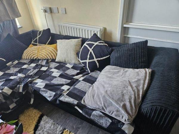 Image 1 of Grey corner sofa. Dog has chewed under the cushion