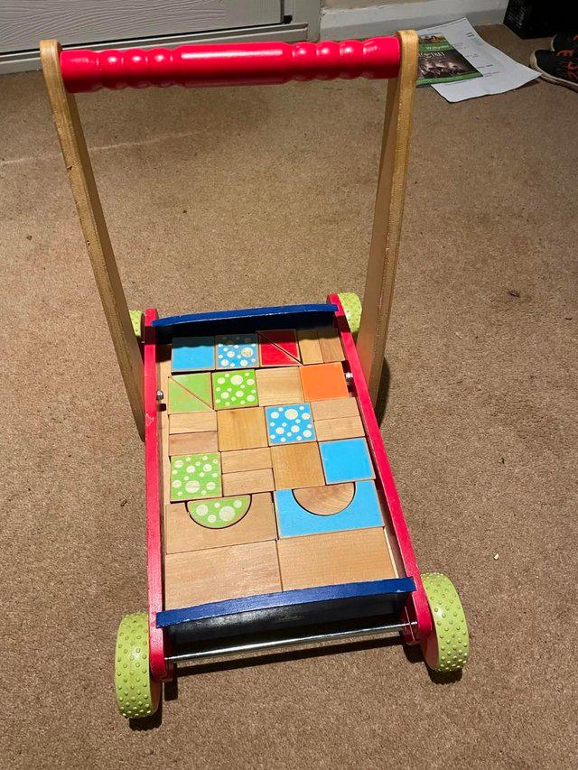 Preview of the first image of childs wooden trolley with various shaped wooden blocks.