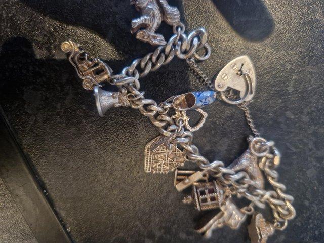 Preview of the first image of Silver marked charm bracelet with 11 charms and heart lock c.