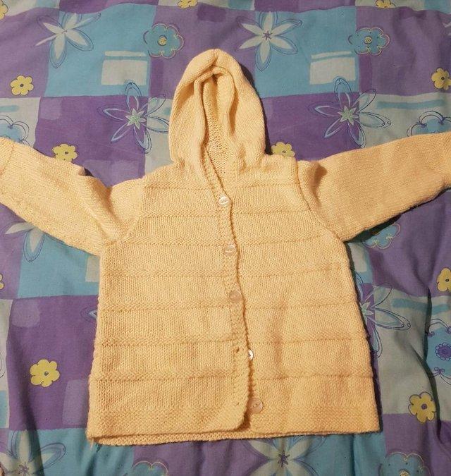Preview of the first image of Baby hand knitted baby cardigans in yellow.