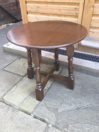 Image 1 of A small , round, wooden coffee table with turned legs.