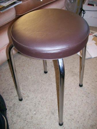 Image 1 of Chrome-legged stool with whitish padded seat pad.