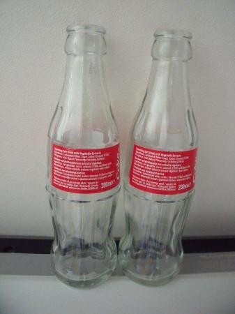 Image 2 of 2 empty glass bottles: Share a Coke with Sarah and Emelio.