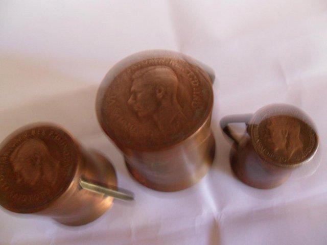 Preview of the first image of Three minature copper mugs with coins for their bases.