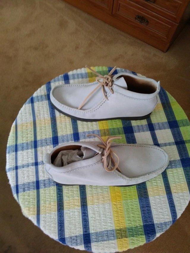 Preview of the first image of A pair of light beige, suede, unisex boat shoes.