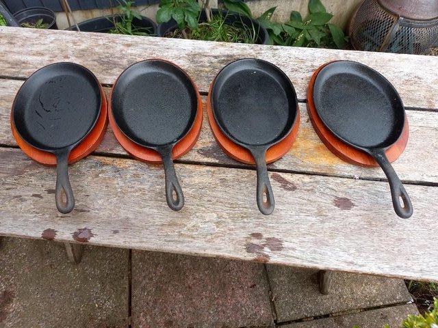 Preview of the first image of 4 iron skillett sizzler pans with wooden shaped tray to fit.