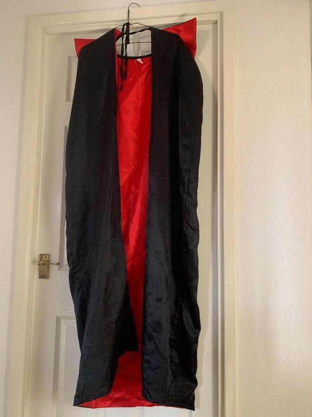 Preview of the first image of HALLOWEEN BLACK CAPE WITH RED COLLAR AND LINING.