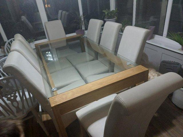 Preview of the first image of Dining table and 8 cream faux leather chairs.