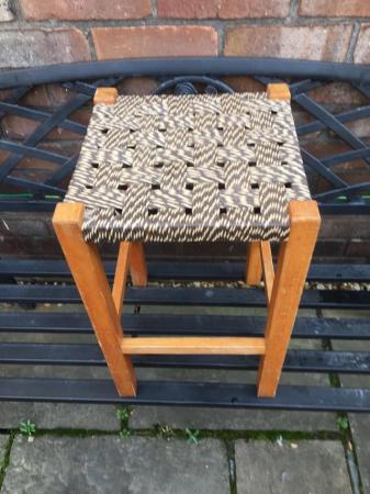 Image 1 of A four legged wooden stool with variegated seat..