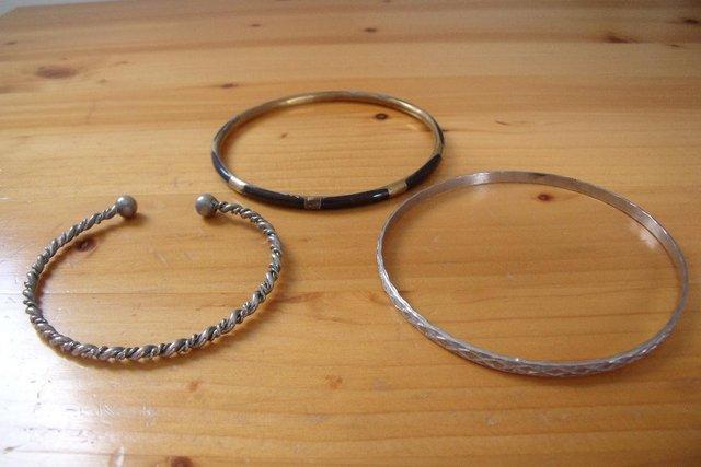 Preview of the first image of 3 bangles:2 silver colour;1 brown/gold colour..