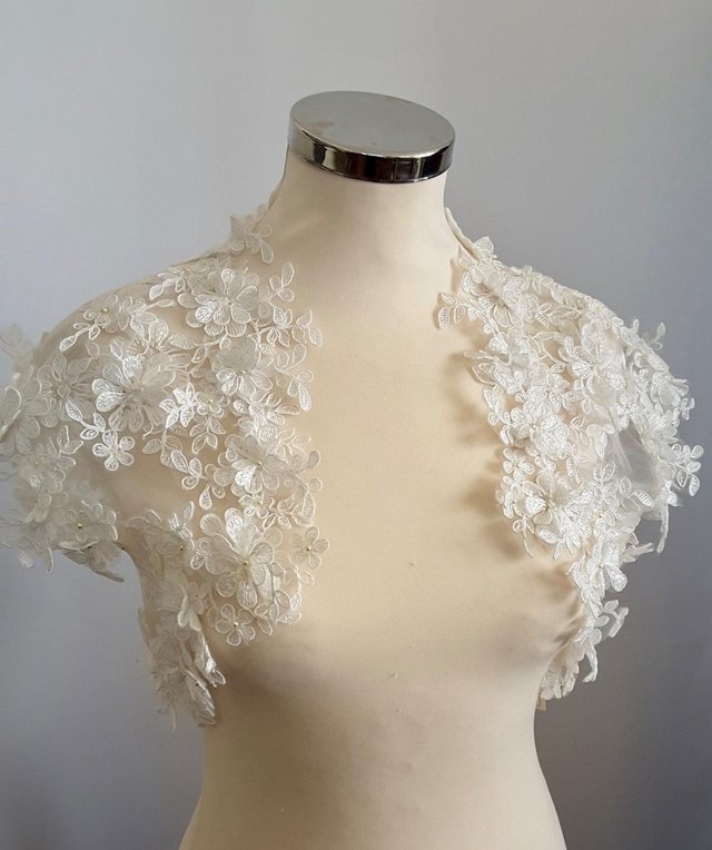 Preview of the first image of Bridal lace bolero in pale ivory with guipure motifs.