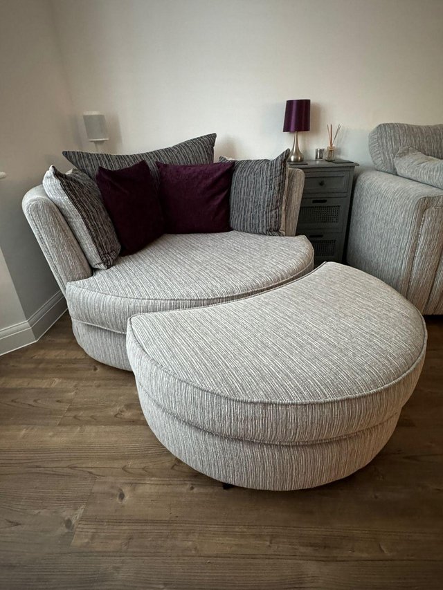 Preview of the first image of Large swivel snuggle chair and half moon footstool.