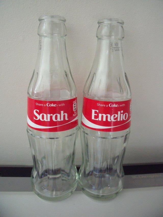 Preview of the first image of 2 empty glass bottles: Share a Coke with Sarah and Emelio..