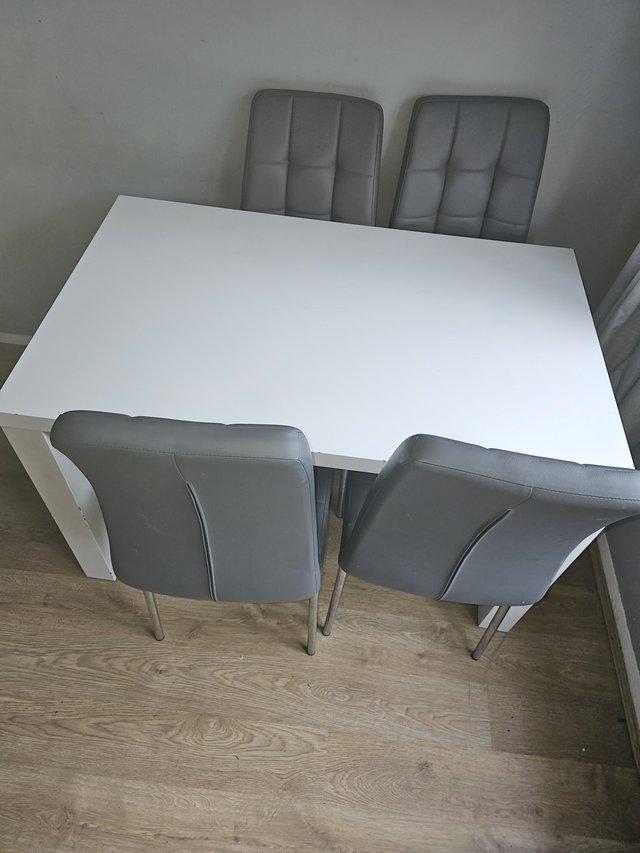 Preview of the first image of White dining table with 4 grey chairs.