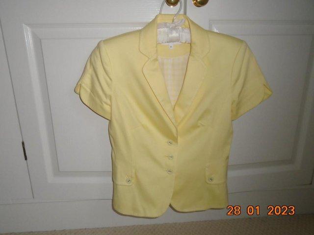 Preview of the first image of Pale yellow short sleeved fitted cotton jacket.